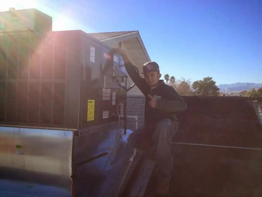HVAC technician performing Air Duct Cleaning on a rooftop unit in East Bay